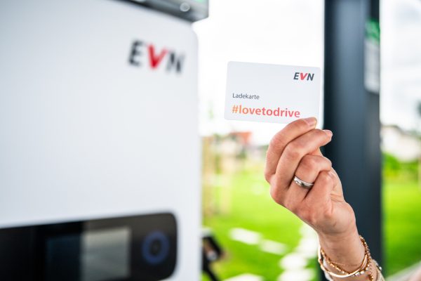 Hand hält EVN-Tankkarte hoch vor Ladestation